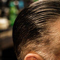 Close-up overhead view of slicked-back dark hair styled with Imperial Blacktop Pomade, showing defined comb lines and high shine.