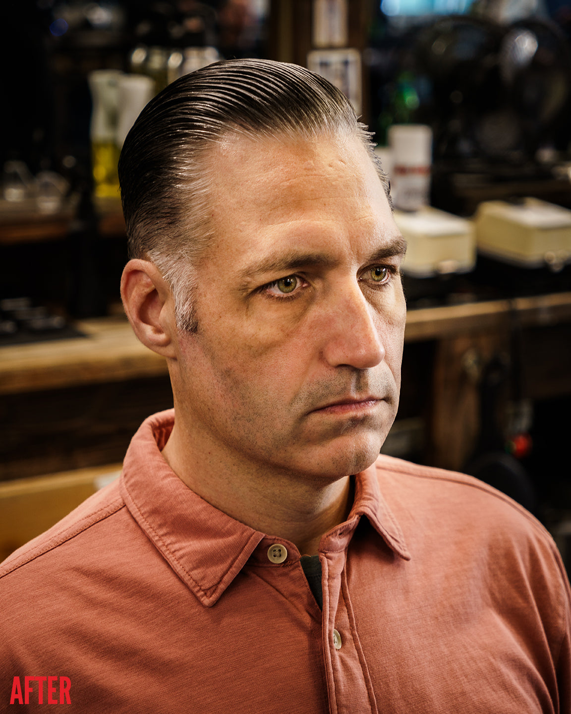 After shot of a man in a barbershop with dark hair slicked back in a clean side-parted style using Imperial Blacktop Pomade.