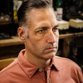 After shot of a man in a barbershop with hair slicked back and parted using Imperial Blacktop Pomade, showing a polished side-swept finish.