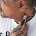 A tattooed man rolls the Imperial Crown Roll cologne applicator along his neck.